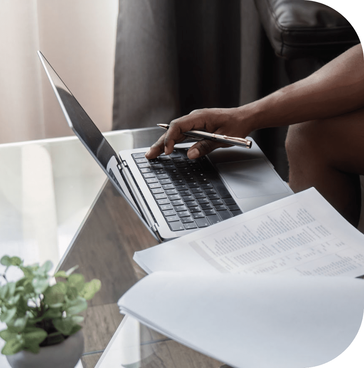 Person working on laptop with documents nearby.